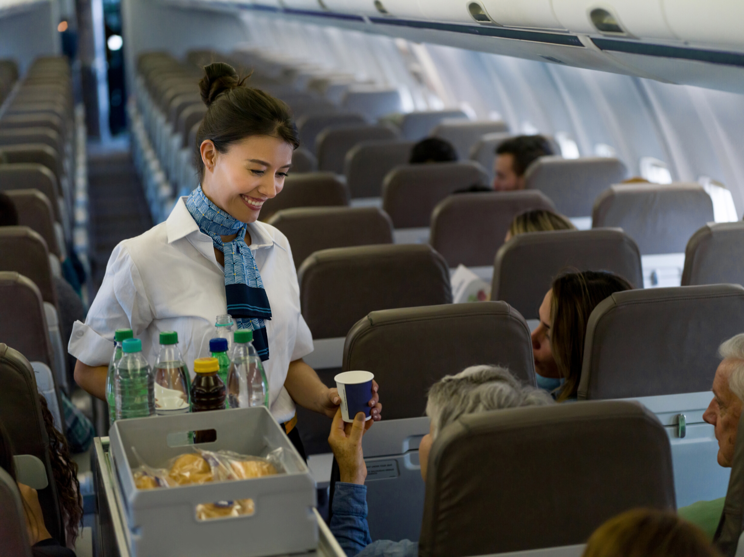 Friendly flight attendant serving drinks in an airplane